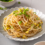 A plate of Korean bean sprout salad on a tiled table.