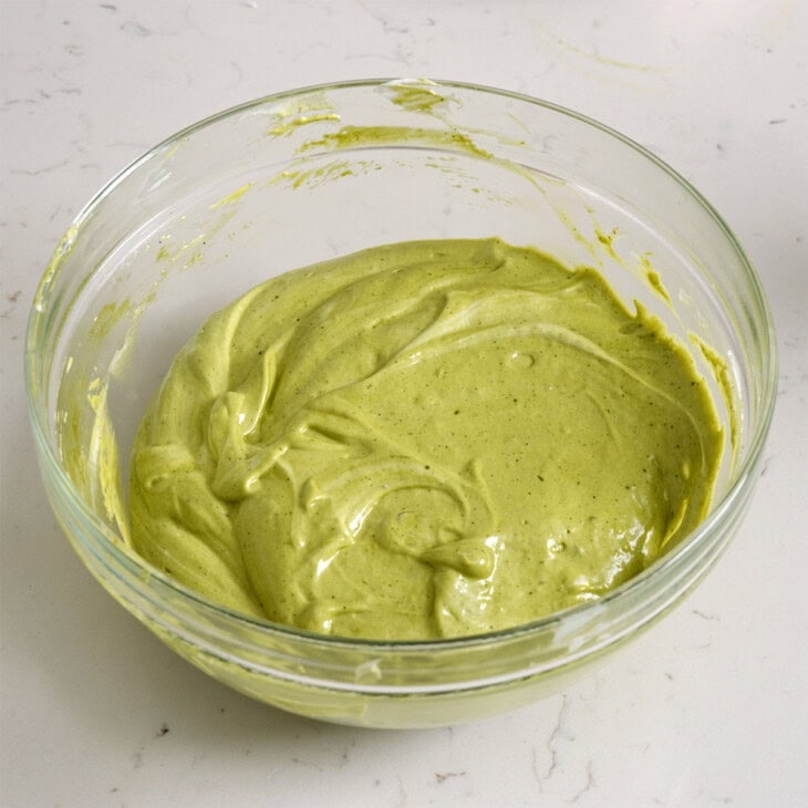 Matcha cake roll batter folded together in a glass bowl.