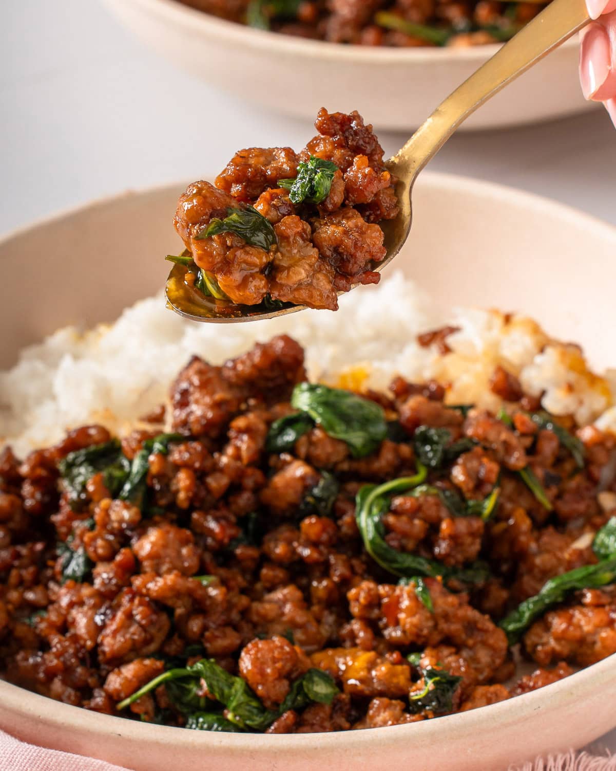 A spoonful of pad kra pao being lifted from a plate.