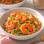 A bowl of shrimp fried rice on a table.