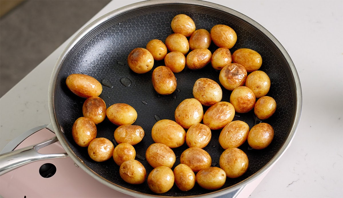 Baby potatoes pan fried in a large deep skillet.