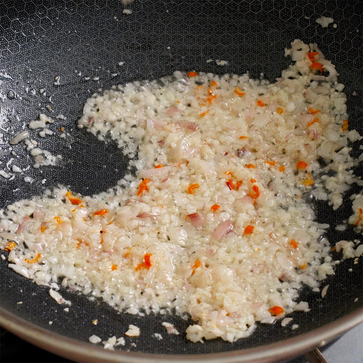 Aromatics beings cooked in a large wok.