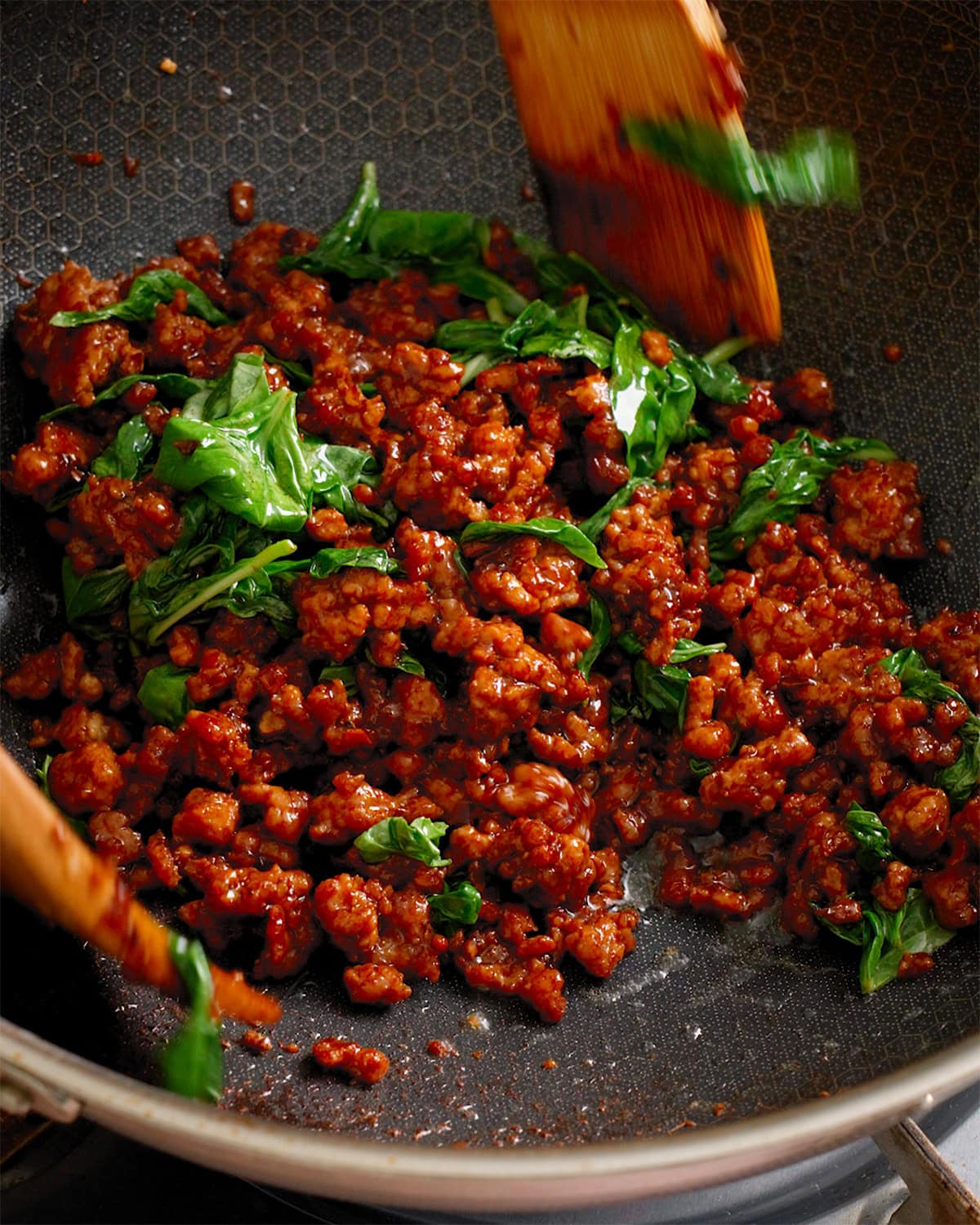 Pad kra pao being tossed together in side a large wok.