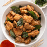 A bowl of Taiwanese popcorn chicken with skewers and dipping sauce nearby.
