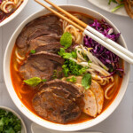 A bowl of bun bo hue with chopsticks and soup spoon.