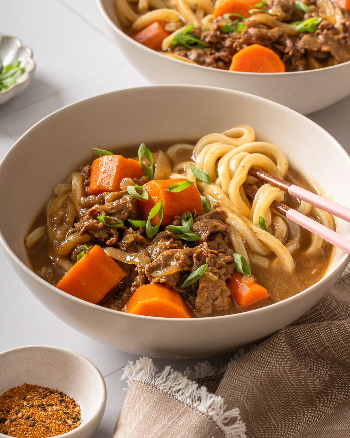 A pair of chopsticks wrapped with udon in a bowl of Japanese curry.