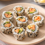 A plate of kani sushi surrounded by table settings.