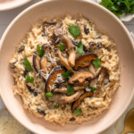 A bowl of mushroom miso risotto surrounded by table settings.