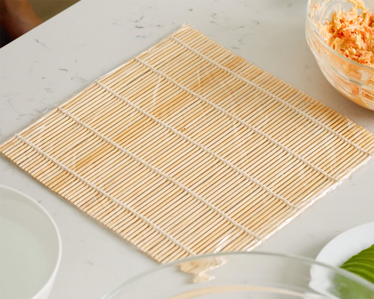 A bamboo mat for sushi wrapped in plastic wrap.