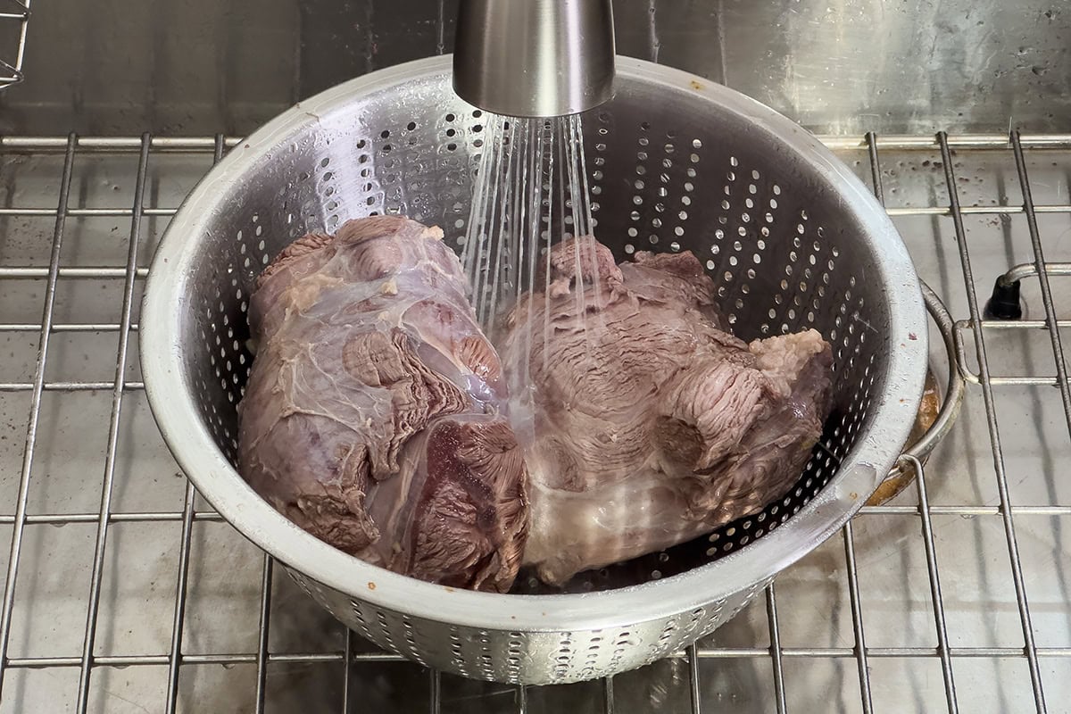 Rinsing the parboiled beef shank.