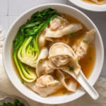 A bowl of wonton soup with a spoon in it.