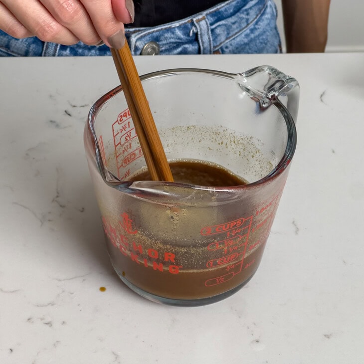 Dissolving a block of Japanese curry roux in a measuring cup with broth.