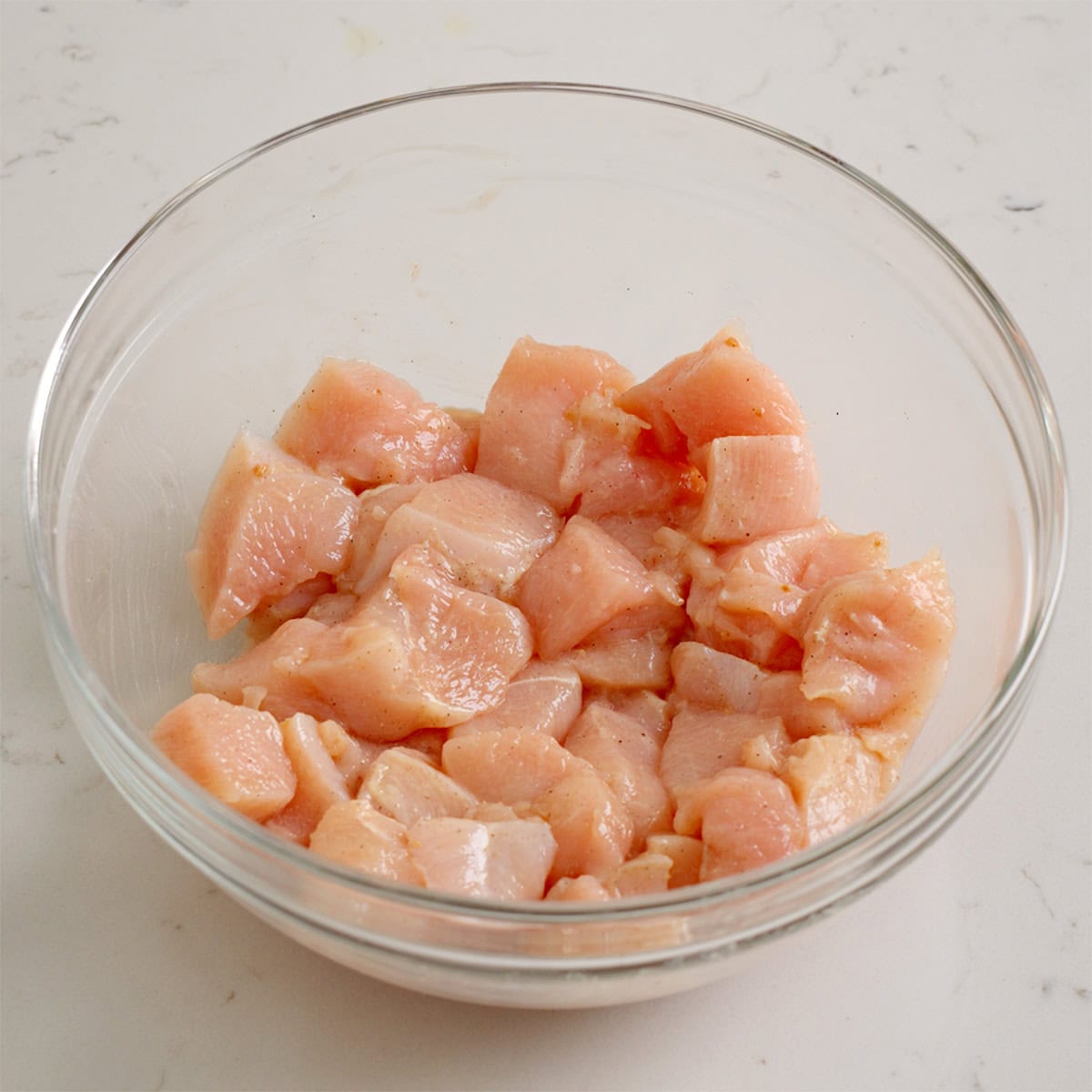 Chicken breast tossed with seasoning in large bowl.