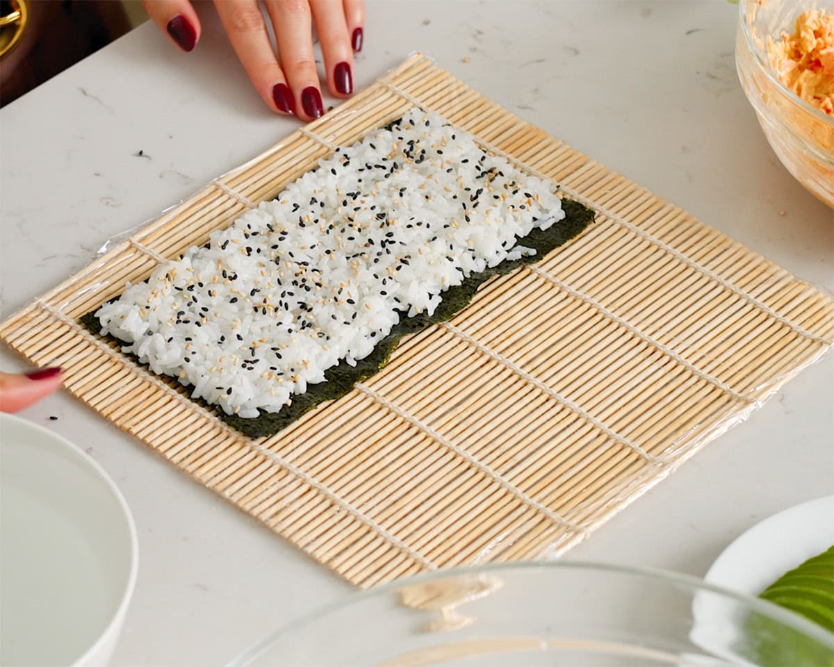 Sushi rice and toasted sesame seeds layered onto a sheet of nori.