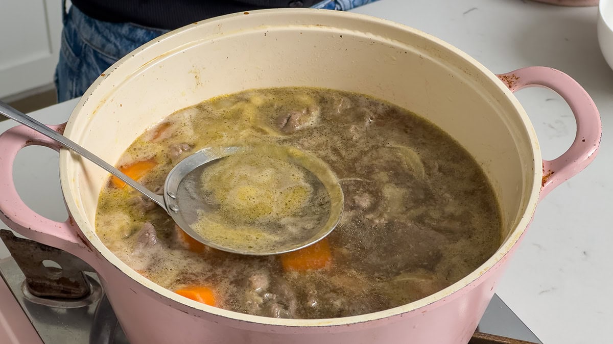 Skimming the broth to remove the scum on top.