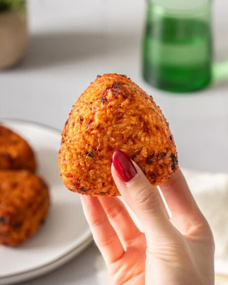 A hand holding up a kimchi rice ball.