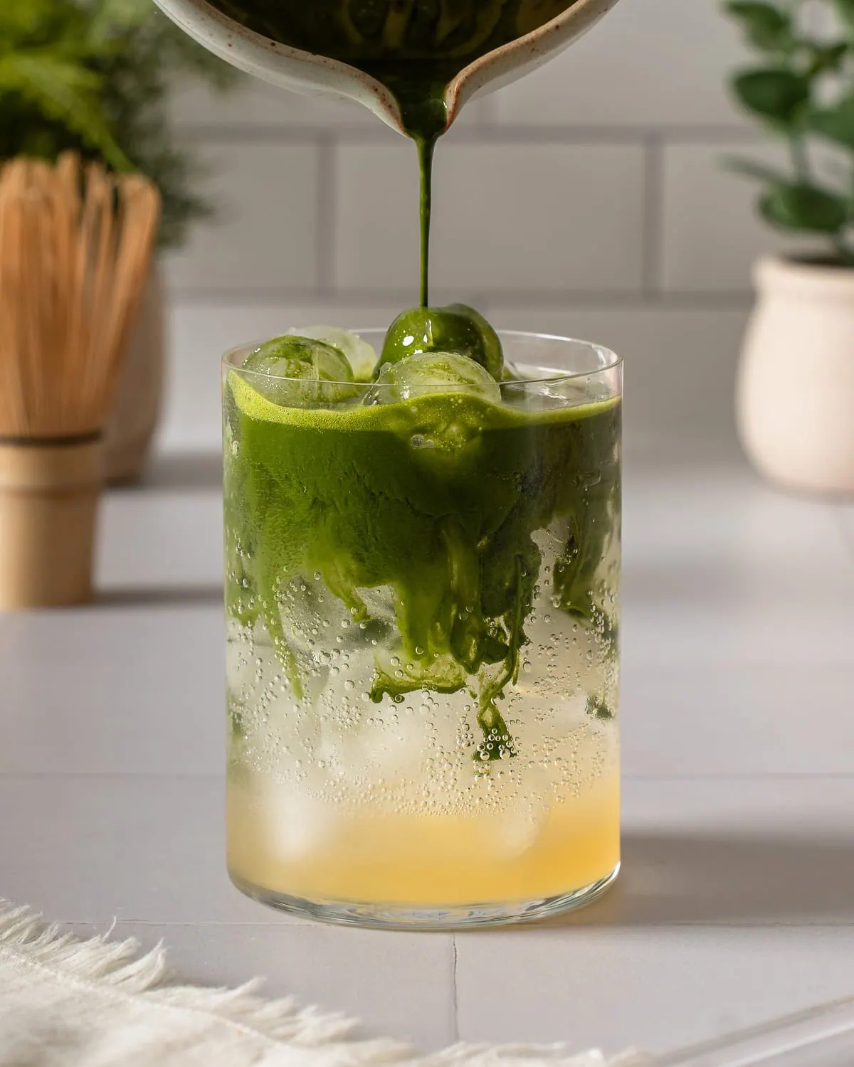 Pouring matcha into a glass of yuzu tonic.