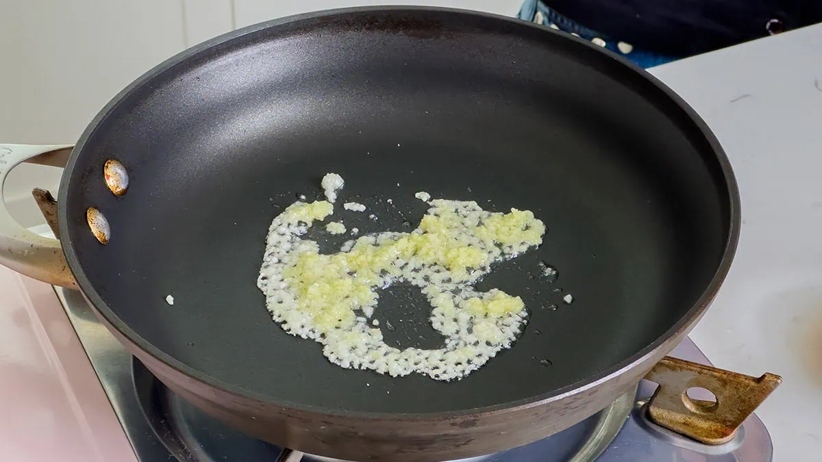 Sautéing minced aromatics in a large skillet.