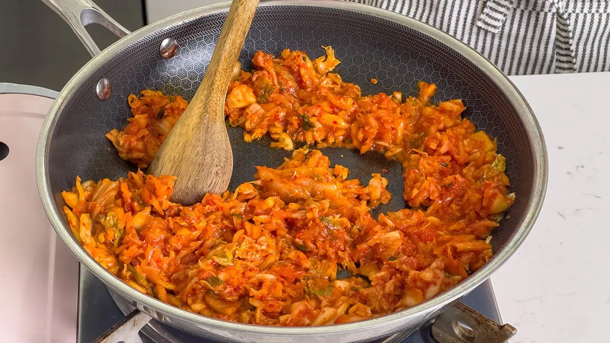 Cooking down chopped kimchi in a large skillet.