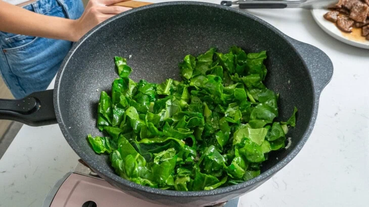 Chinese brocolli cooking inside a wok.