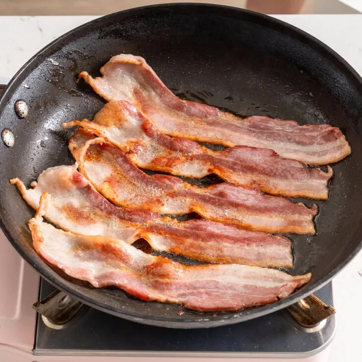 Cooking bacon in a large skillet.