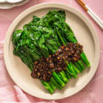 A top down view of a plate of gai lan with oyster sauce.