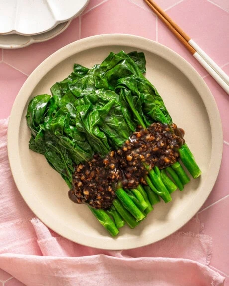 A top down view of a plate of gai lan with oyster sauce.