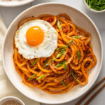 A top down view of kimchi udon surrounded by table settings.