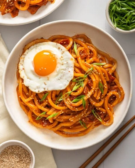 A top down view of kimchi udon surrounded by table settings.