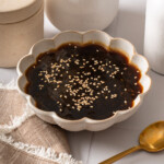 A bowl of teriyaki sauce topped with toasted sesame seeds.