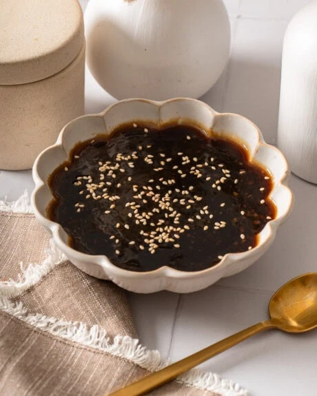 A bowl of teriyaki sauce topped with toasted sesame seeds.