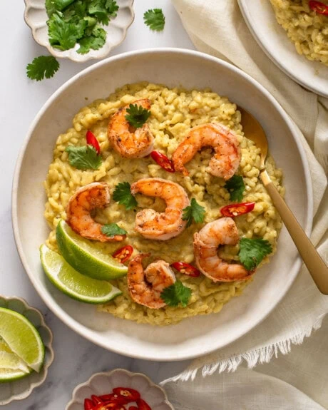 A top down view of a plate of Thai Green curry risotto with a spoon in it.