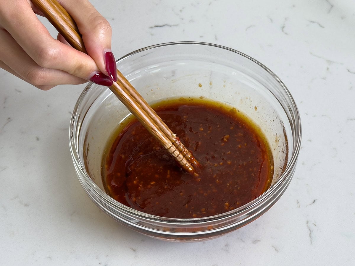 Mixing together gochujang sauce in a small bowl.