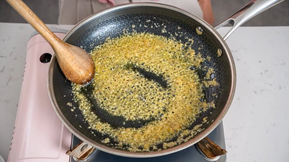 Sautéing minced aromatics in a large skillet.