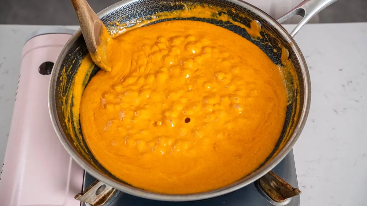 Mixing together a gochujang cream sauce in a large skillet.