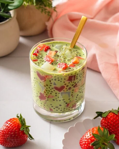 A cup full of strawberry matcha sago with a spoon in it.