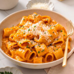 A plate of gochujang pasta surrounded by table settings.