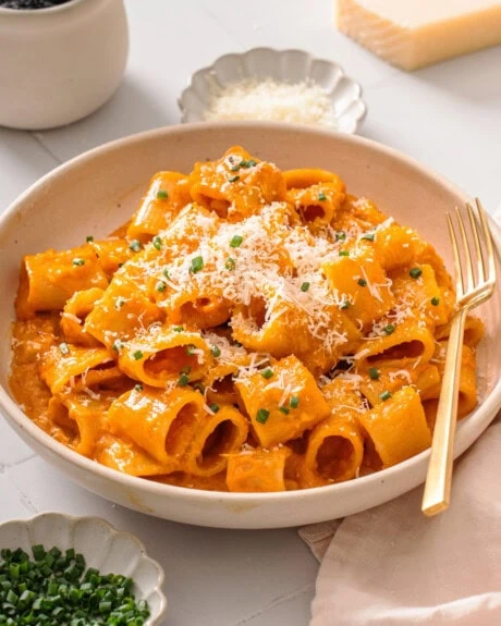 A plate of gochujang pasta surrounded by table settings.