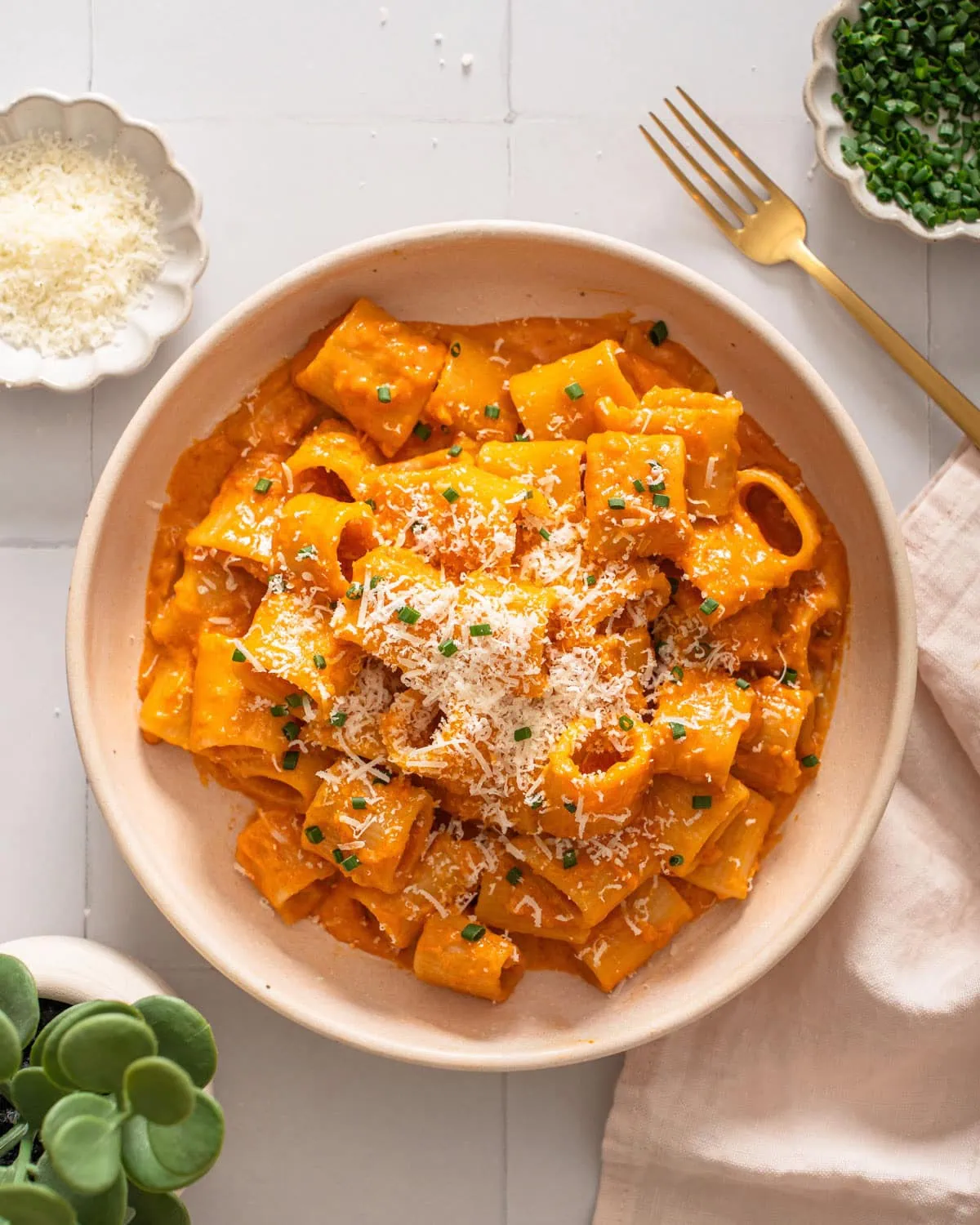 A top down view of a plate of gochujang pasta surrounded by table settings.