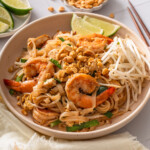 A plate of shrimp pad thai surrounded by extra garnishes.