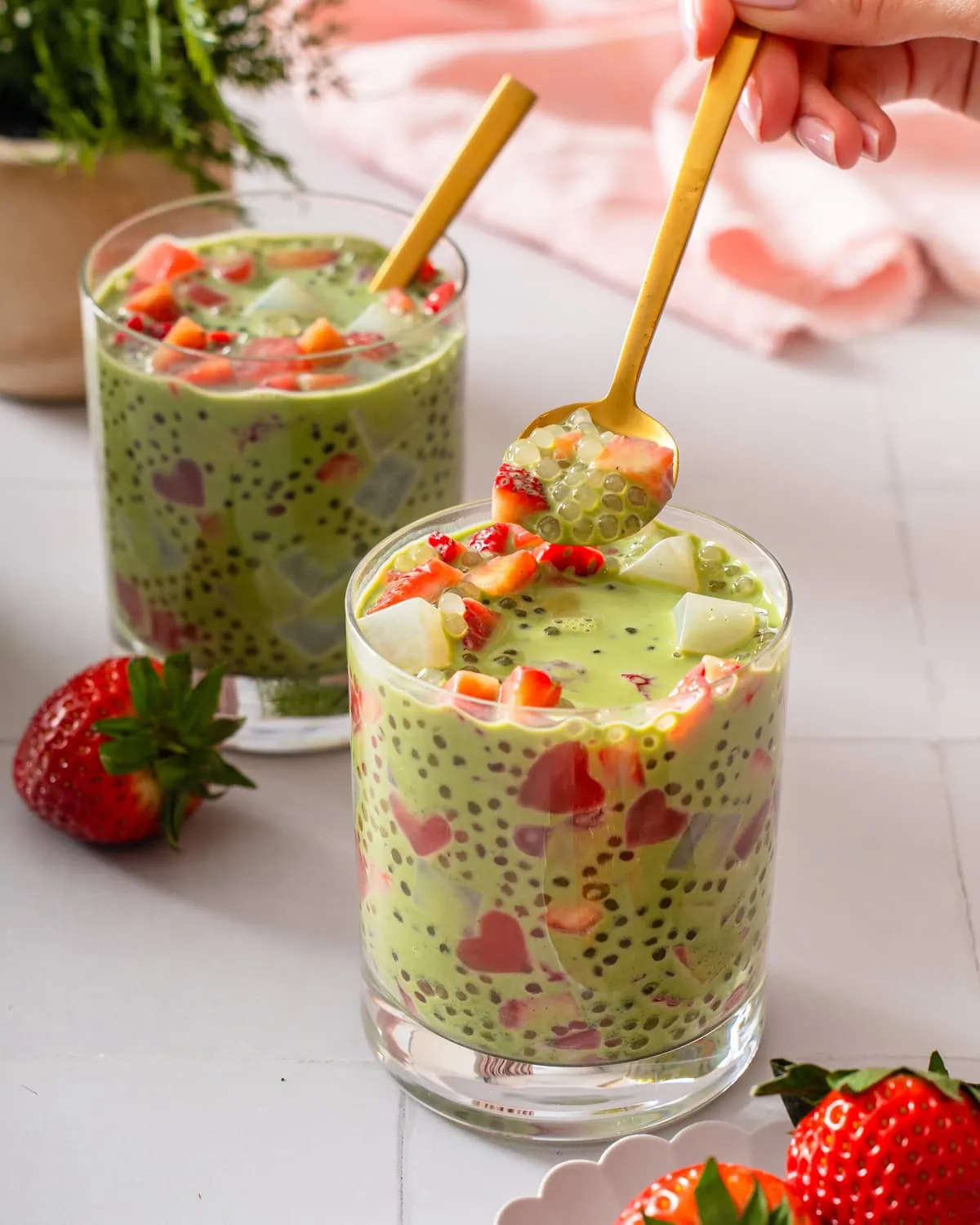 A spoonful of strawberry matcha sago being lifted from a cup.