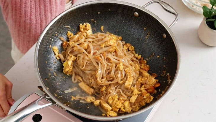 Pad Thai noodles, sauce, and mix in combined together in a wok.