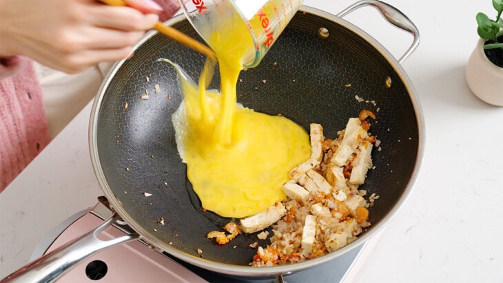Pouring in eggs into a wok.