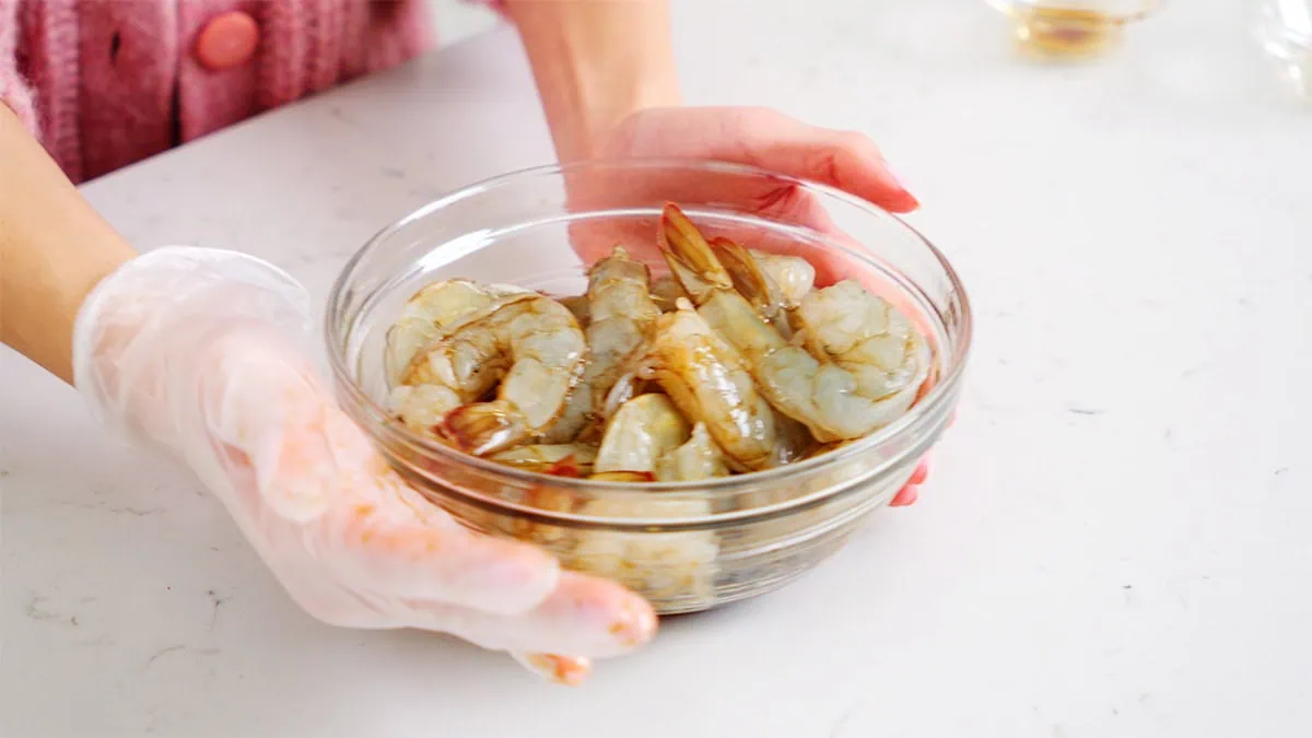 Shrimp tossed in seasoning in a small bowl.