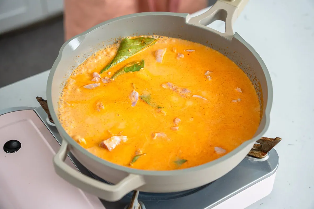 Chicken cooking in coconut milk and seasonings.