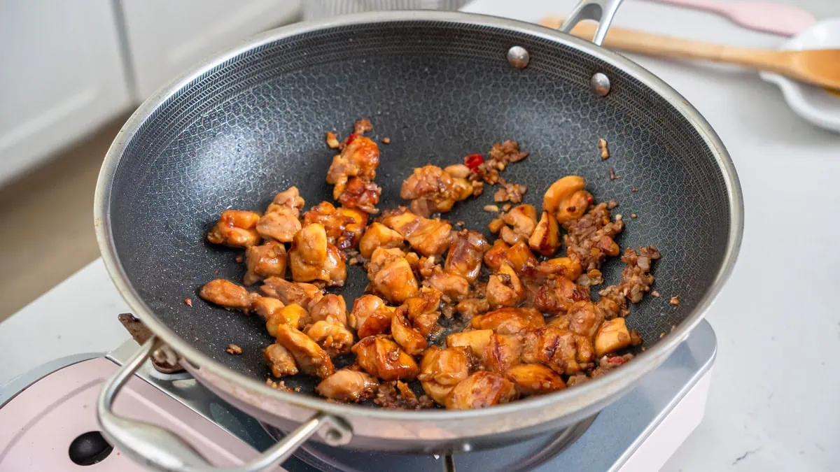 Chicken and aromatics cooked inside a large wok.