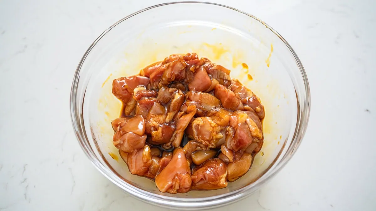 A bowl of chicken thighs being marinaded.