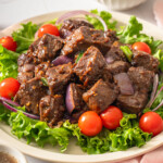 A close up of a plate of bo luc lac.