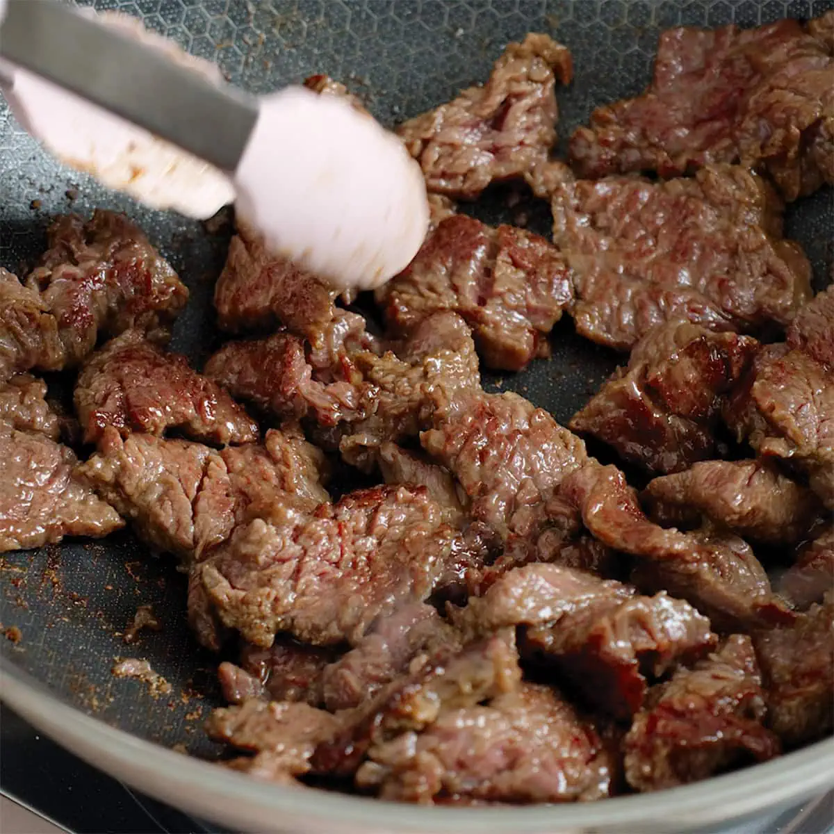 Cooking flank steak in a large wok.