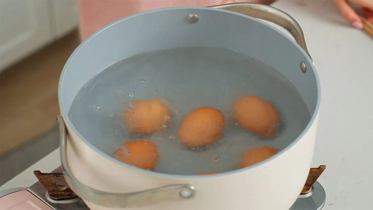 Eggs softly boiling in a large pot of water.